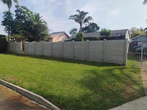 una cerca frente a un patio con hierba en Puravida guesthouse, en Umkomaas