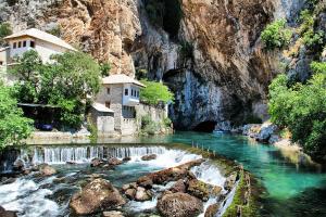a river with a building on the side of a mountain at Apartman Dali in Blagaj