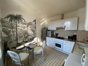 une cuisine avec des armoires blanches et une table et des chaises dans l'établissement LE DARCET - Hypercentre - Calme - Proche Gare & Thermes, à Vichy