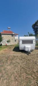 a white truck parked in a field next to a house at Unique night in a cozy caravan in Lezhë