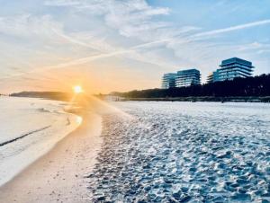 a beach with the sun setting behind some buildings at Your Holidays Waves Panorama D866 in Międzyzdroje