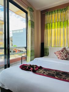 a bedroom with two beds and a large window at Hotel Bardan in Pokhara