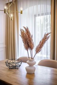 une table avec un vase contenant des plantes séchées dans l'établissement Beňovský Apartments, à Poprad