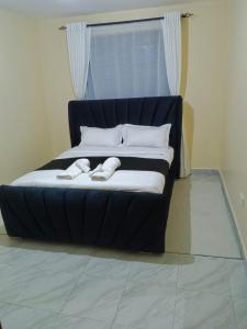 a black bed with two slippers on top of it at Luqman Apartments in Meru