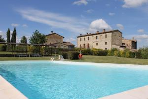 a large blue swimming pool in front of a building at Country Home Tuscany - Courtyard Room in Lano