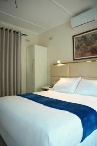 a bedroom with a large white bed with a blue blanket at Neat standard room in guesthouse - 2088 in Bulawayo
