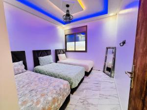 two beds in a room with purple walls at Happy Monkey Villa Taghazout in Aït Ahmed +29 photos