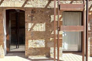 a brick building with two windows and a bench at Cal Teixidor in Mediona