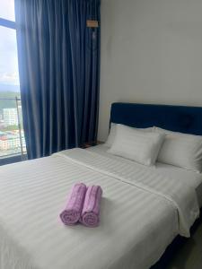 deux pantoufles violettes posées sur un lit avec une fenêtre dans l'établissement Sungna Homestay, à Kota Kinabalu