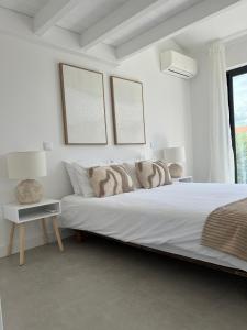 a white bedroom with a large bed and a window at Casa Beliche in Aljezur
