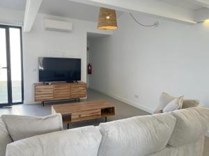 a living room with a white couch and a tv at Casa Beliche in Aljezur