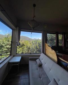 a living room with a couch and a large window at Loft Urucum a 700 metros da vila-Vale do Capao in Palmeiras