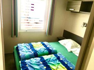 a small bedroom with a bed with a window at Charming Mobile Home in Argels-sur-Mer with Stunning Beach Views in Argelès-sur-Mer