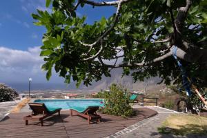 a swimming pool with two chairs and a tree at Apartamento con Vistas, Piscina y Tenis en El Hierro in Tigaday