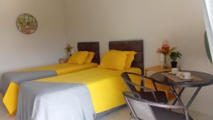 zwei Betten in einem Zimmer mit Tisch und Stühlen in der Unterkunft Korah House in Saint Philip