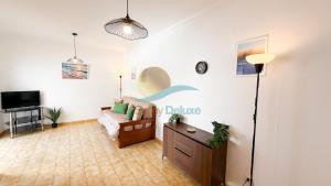 a living room with a couch and a tv at Casa Tropical by Sunny Deluxe in Armação de Pêra