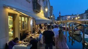 a group of people sitting at tables outside a building at LE RIVE Casa Vacanza La Ciosà in Chioggia