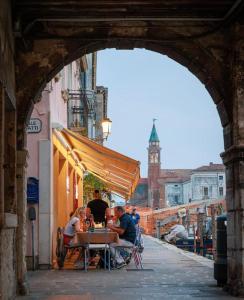 a group of people sitting at a table under an archway at LE RIVE Casa Vacanza La Ciosà in Chioggia