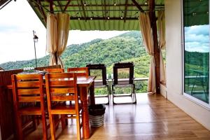 a dining room with a table and chairs and a large window at Kirin Farm in Chiang Mai