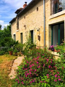 una casa in pietra con fiori rosa di fronte di Appartement à l'Aujardière a Durtal
