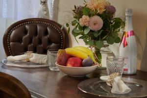 a table with a bowl of fruit and a vase of flowers at Apartman Charlotte v Dome so studňou na streche in Banská Štiavnica +12 photos