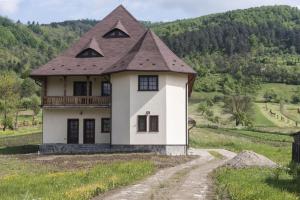 Pensiunea Sanziene في Strîmtura: منزل أبيض مع سقف بني على تلة