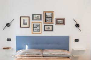 a bedroom with a blue headboard and framed pictures on the wall at Trilocale con piscina in Caprino Veronese