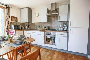 a kitchen with white cabinets and a wooden table with a dining room at Charming Apartment - City Centre - Free Parking, Self-Check-In, Balcony and Smart TV with Sky TV and Netflix by Yoko Property in Milton Keynes