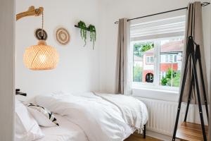 a white bedroom with a bed and a window at Hilton House - stylish 4-bed with parking in Manchester