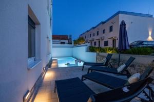 patio con sedie, ombrellone e piscina di Apartment with private Swimming pool a Trogir Altre 8 foto