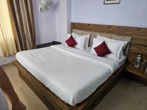 a bed with white sheets and red pillows at Green Valley Waknaghat by Vairagya Hospitality in Kandāghāt