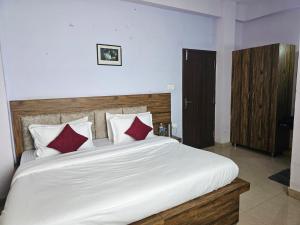 a bedroom with a large white bed with red pillows at Green Valley Waknaghat by Vairagya Hospitality in Kandāghāt +3 photos