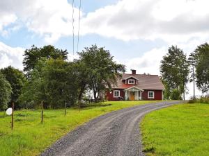 una casa roja en una colina con un camino de tierra en 5 person holiday home in HÄRADSBÄCK, en Häradsbäck