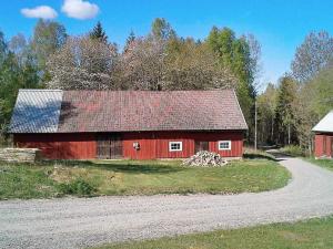 un granero rojo al costado de una carretera en 5 person holiday home in HÄRADSBÄCK, en Häradsbäck