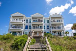 a large white building on the beach with stairs at Whispering Sands 1A in Coffeyville