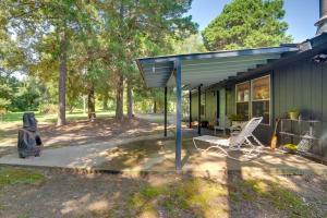una casa verde con un porche y una silla en Secluded Getaway on about 10 Acres in The Piney Woods!, en Winnsboro