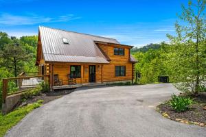 a log home with a driveway in front at Rustic Retreat By Avada Properties in Greystone Heights