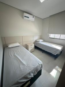 two beds in a small room with two windows at Apartamento Prime 02 in Palmas +5 photos