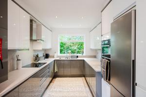 a kitchen with white cabinets and a window at Hilton House - stylish 4-bed with parking in Manchester