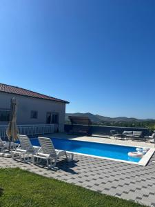 a swimming pool with two chairs and an umbrella at Kuća za odmor ''ANA'' in Čitluk