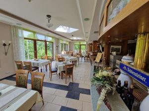 a restaurant with white tables and chairs and windows at Burgschänke, Hotel & Restaurant - E-Mobilität Ladestationen für Elektroautos in Burgthann