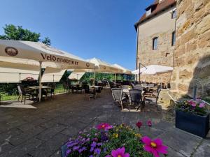an outdoor patio with tables and chairs and flowers at Burgschänke, Hotel & Restaurant - E-Mobilität Ladestationen für Elektroautos in Burgthann
