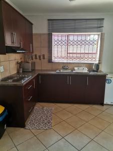 eine Küche mit braunen Schränken und einem Fenster in der Unterkunft NEMARA Self Catering Lodge in Polokwane