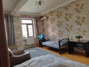 a bedroom with a bed and a desk and a window at Royal 2-room apartment in Dushanbe