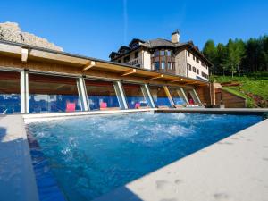 a swimming pool in front of a house at Hotel Garni Gonzaga in Canazei