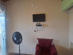 a room with a fan and a couch and a television at Casa de Luz - Lar na Serra - Suite - Duplo ou Triplo - N4 in Miguel Pereira