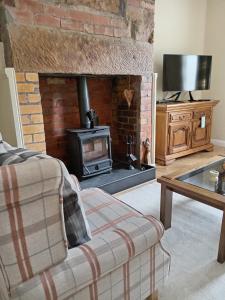 a living room with a brick fireplace and a couch at Birchwood Cottage - In the Heart of Wooler in Wooler