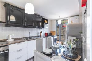 een keuken met witte kasten, een tafel en een koelkast bij Vista Mar by Atlantic Holiday in Caniço