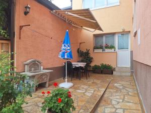 un patio con una mesa y una sombrilla azul en Kaya Apartments, en Sarajevo