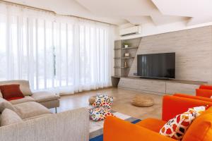 a living room with orange furniture and a flat screen tv at Hossana 5BHK Private Villa with Pool near Kovalam Beach in Kovalam